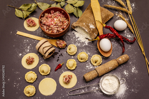 Composition with raw dumplings and ingredients on trendy black stone concrete background. Process of cooking