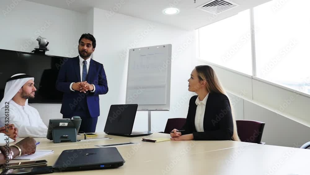 Mixed business team in Dubai. Business meeting with men wearing kandura and western people in the office Mixed business team in Dubai. Business meeting with men wearing kandura and western people in the office