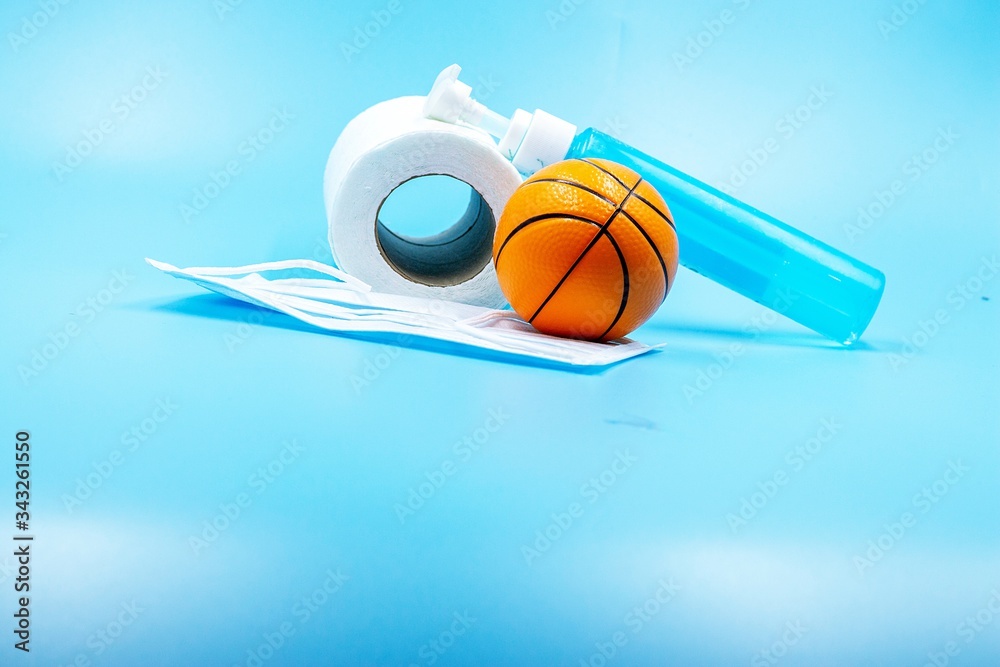 Basketball with toilet tissue and hand gel on blue background