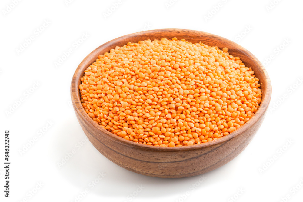 Raw uncooked lentils in a wooden bowl isolated on white background. Side view. Raw uncooked lentils in a wooden bowl isolated on white background. Side view.