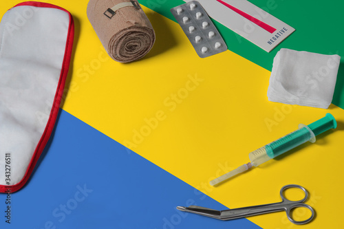 Gabon flag with first aid medical kit on wooden table background. National healthcare system concept, medical theme.