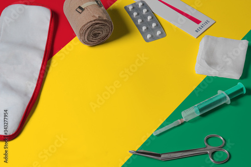 Guinea Bissau flag with first aid medical kit on wooden table background. National healthcare system concept, medical theme.