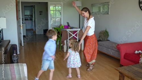 Young mother and two children dancing and having fun at home during coronavirus quarantine