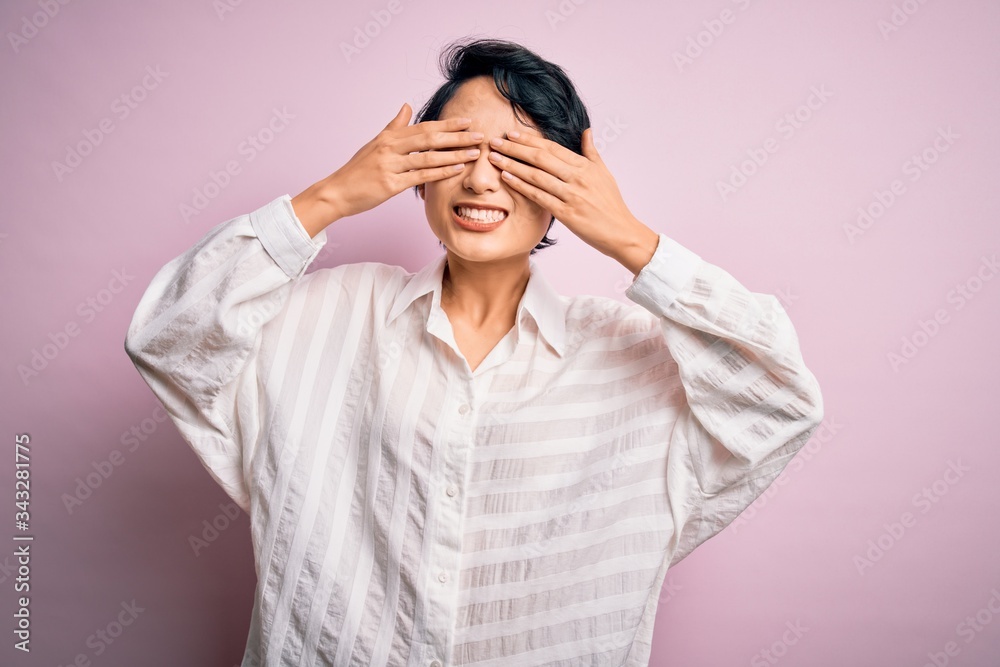 Young beautiful asian girl wearing casual shirt standing over isolated pink background covering eyes with hands smiling cheerful and funny. Blind concept. Young beautiful asian girl wearing casual shirt standing over isolated pink background covering eyes with hands smiling cheerful and funny. Blind concept.