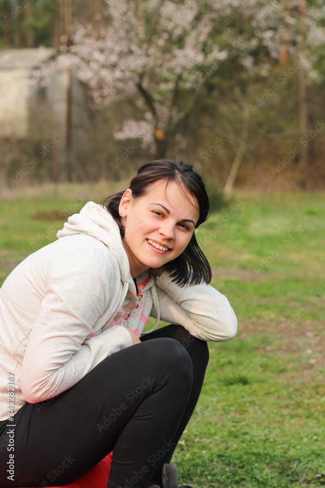 smiling brunette girl in casual clothes sitting on blurred green natural background smiling brunette girl in casual clothes sitting on blurred green natural background
