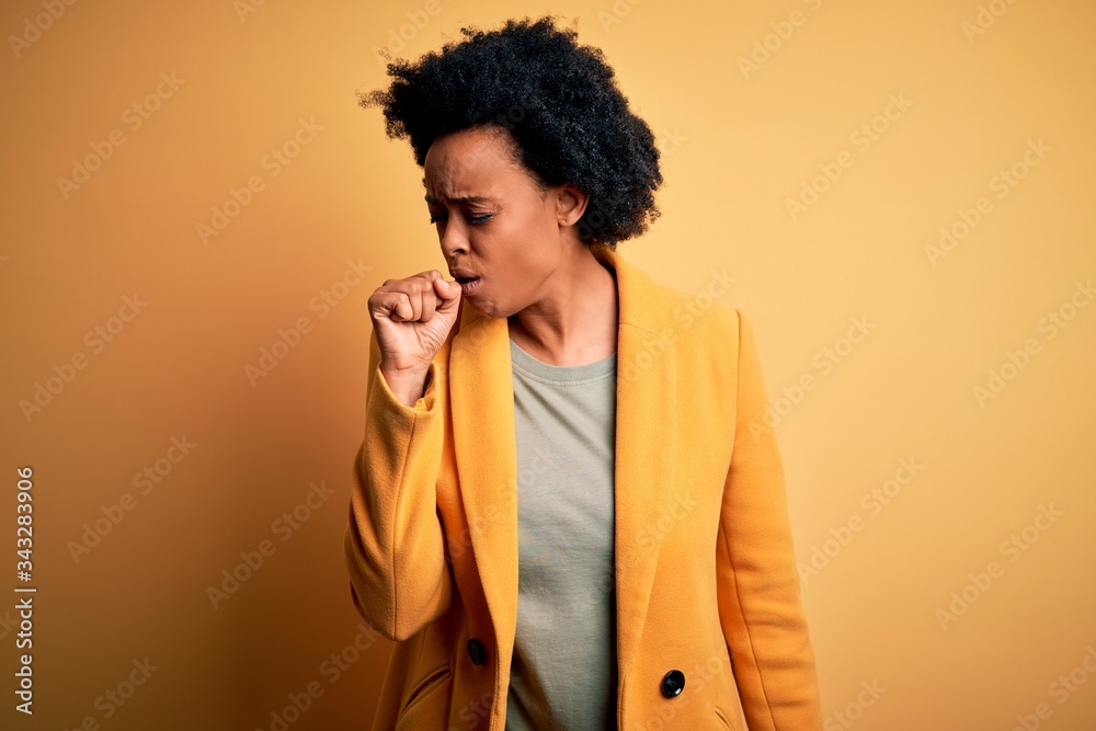 Young beautiful African American afro businesswoman with curly hair wearing yellow jacket feeling unwell and coughing as symptom for cold or bronchitis. Health care concept. Young beautiful African American afro businesswoman with curly hair wearing yellow jacket feeling unwell and coughing as symptom for cold or bronchitis. Health care concept.