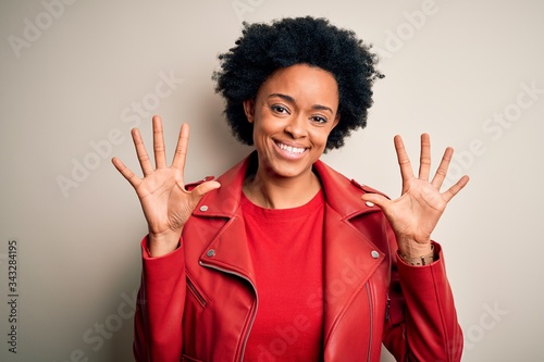 Young beautiful African American afro woman with curly hair wearing casual red jacket showing and pointing up with fingers number ten while smiling confident and happy.
