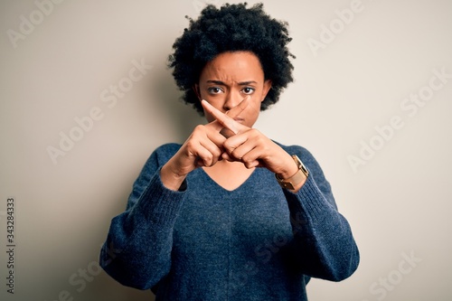 Young beautiful African American afro woman with curly hair wearing casual sweater Rejection expression crossing fingers doing negative sign