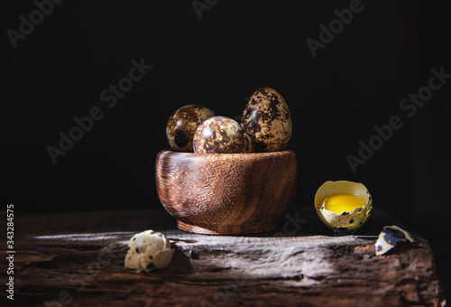 quail eggs in a wooden bowl .dark photography. photo