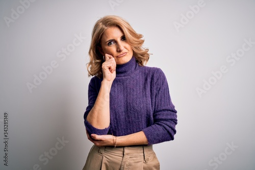 Middle age beautiful blonde woman wearing purple turtleneck sweater over white background thinking looking tired and bored with depression problems with crossed arms.