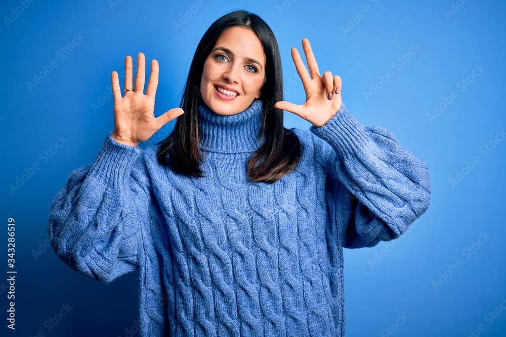 Young brunette woman with blue eyes wearing casual turtleneck sweater showing and pointing up with fingers number eight while smiling confident and happy. Young brunette woman with blue eyes wearing casual turtleneck sweater showing and pointing up with fingers number eight while smiling confident and happy.