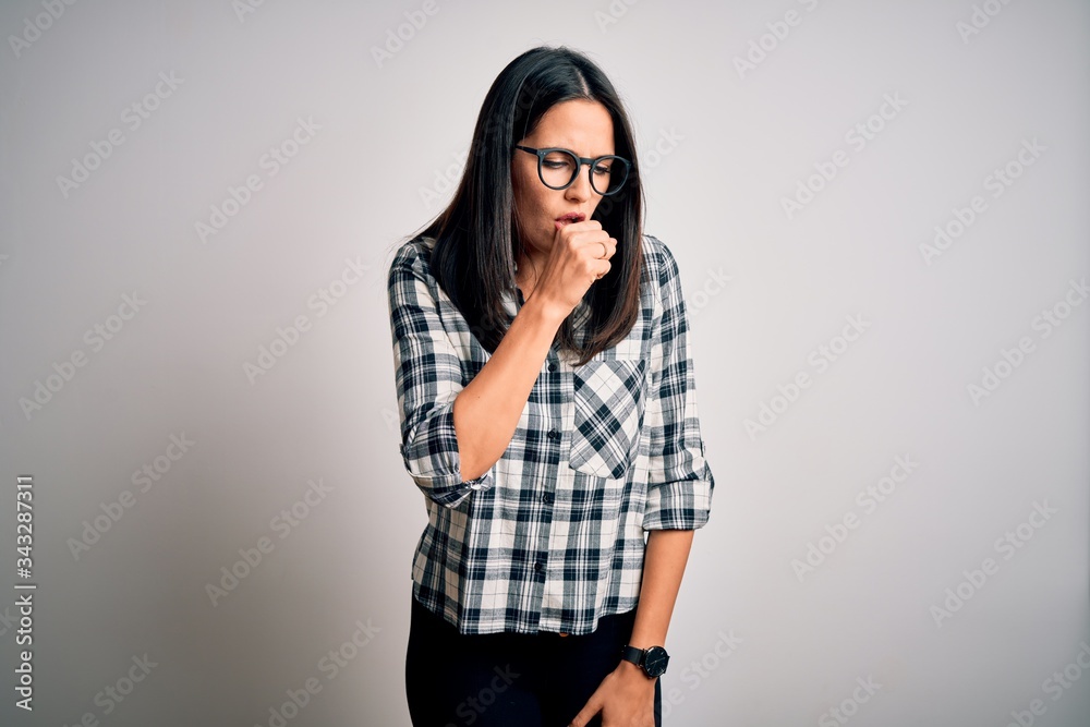 Young brunette woman with blue eyes wearing casual shirt and glasses over white background feeling unwell and coughing as symptom for cold or bronchitis. Health care concept. Young brunette woman with blue eyes wearing casual shirt and glasses over white background feeling unwell and coughing as symptom for cold or bronchitis. Health care concept.