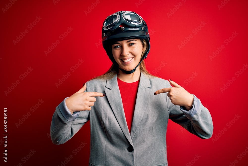 Young beautiful blonde motorcyclist woman wearing motorcycle helmet over red background looking confident with smile on face, pointing oneself with fingers proud and happy. Young beautiful blonde motorcyclist woman wearing motorcycle helmet over red background looking confident with smile on face, pointing oneself with fingers proud and happy.