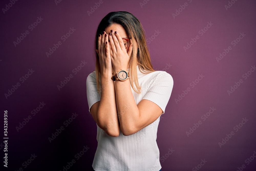 Young beautiful blonde woman with blue eyes wearing casual t-shirt over purple background with sad expression covering face with hands while crying. Depression concept. Young beautiful blonde woman with blue eyes wearing casual t-shirt over purple background with sad expression covering face with hands while crying. Depression concept.