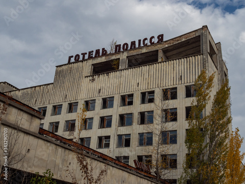 Hotel Polissia in abandoned ghost town Pripyat. Overgrown trees and collapsing buildings in Pripyat, Chernobyl exclusion zone. Inscription on roof - Hotel Polissya. Ukraine photo