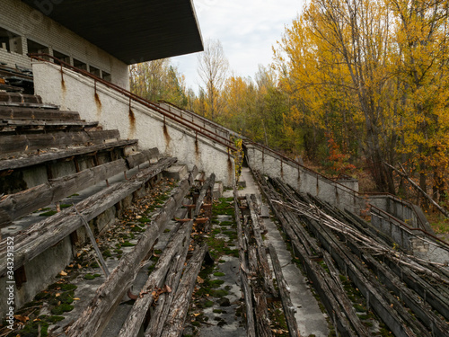 Abandoned decaying tribune of sport stadium Avangard, taken by nature in Pripyat ghost town in Chernobyl Exclusion Zone. Ukraine photo