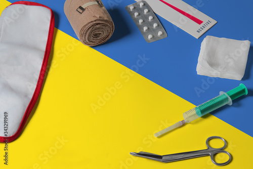 Ukraine flag with first aid medical kit on wooden table background. National healthcare system concept, medical theme.