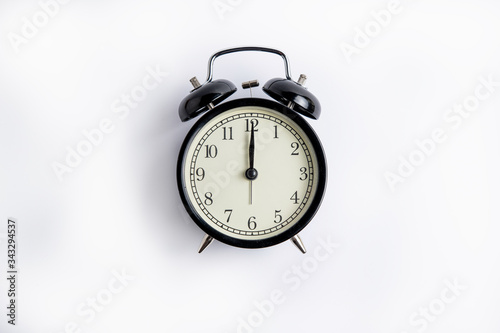 black alarm clock on a white background, on the dial 12 o'clock, alarm clock on 6