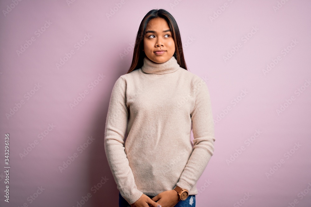 Fototapeta premium Young beautiful asian girl wearing casual turtleneck sweater over isolated pink background smiling looking to the side and staring away thinking.