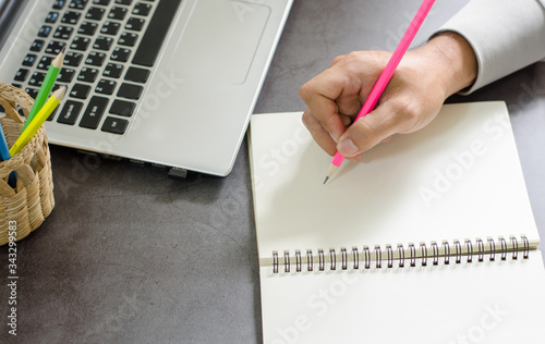 Close up of.the hand of a business planning or taking notes and laptop on your desk at home. to quarantine against the virus Covid-19
