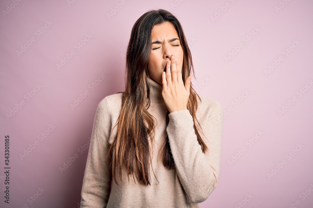 Young beautiful girl wearing casual turtleneck sweater standing over isolated pink background bored yawning tired covering mouth with hand. Restless and sleepiness. Young beautiful girl wearing casual turtleneck sweater standing over isolated pink background bored yawning tired covering mouth with hand. Restless and sleepiness.