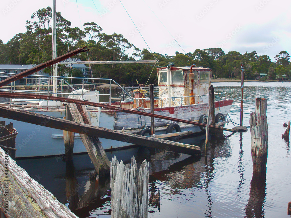 Old timber fishing boat moored at a rundown jetty