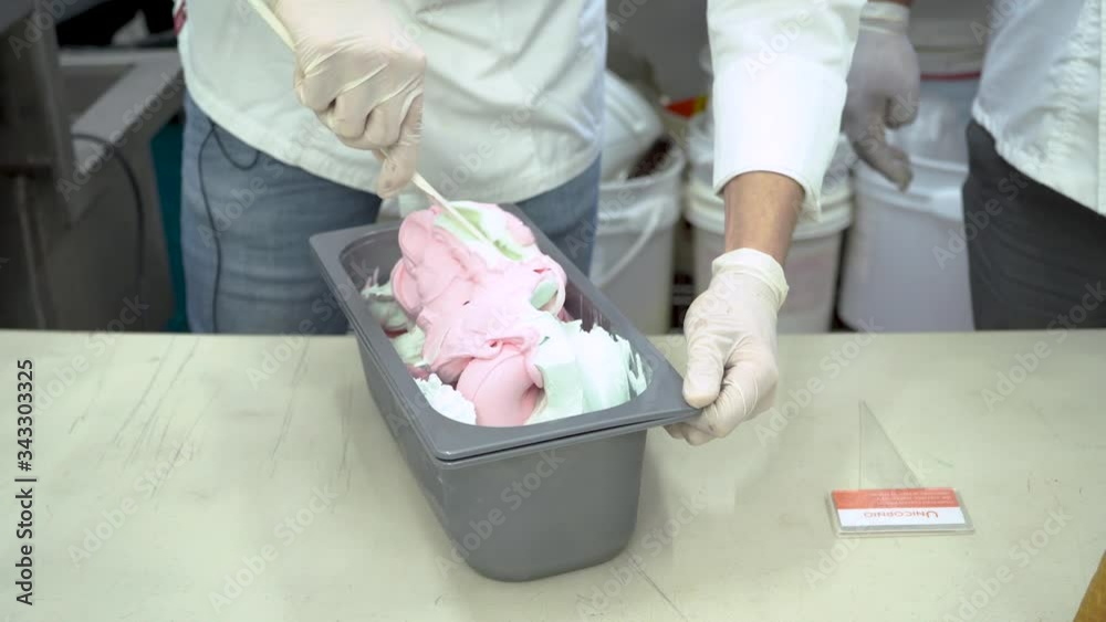 Hands with latex gloves mixing ice cream in container. Static, high angle Hands with latex gloves mixing ice cream in container. Static, high angle