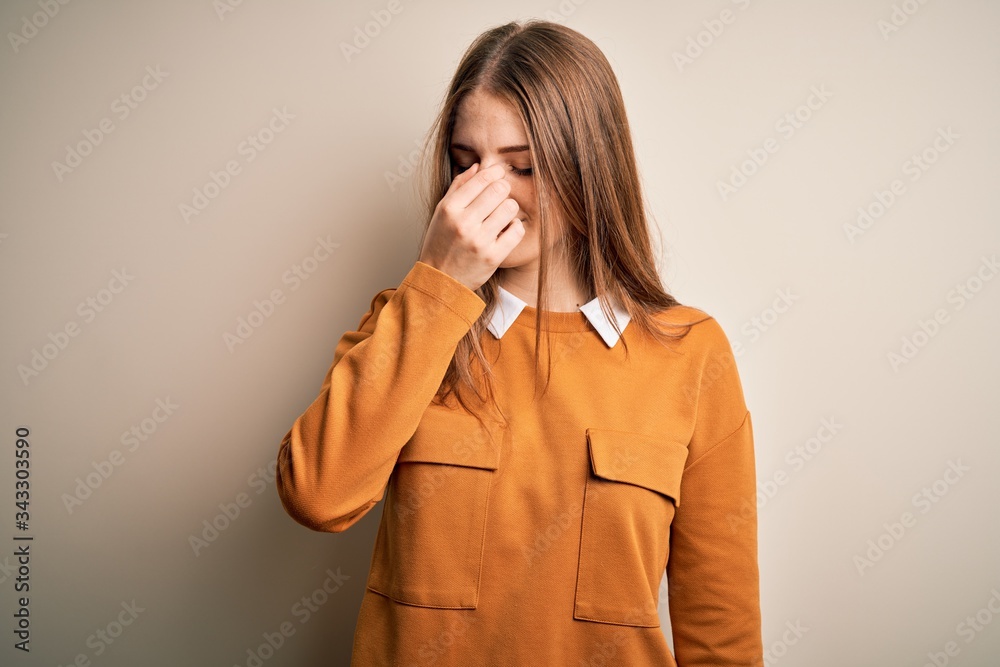 Young beautiful redhead woman wearing casual sweater over isolated white background tired rubbing nose and eyes feeling fatigue and headache. Stress and frustration concept. Young beautiful redhead woman wearing casual sweater over isolated white background tired rubbing nose and eyes feeling fatigue and headache. Stress and frustration concept.