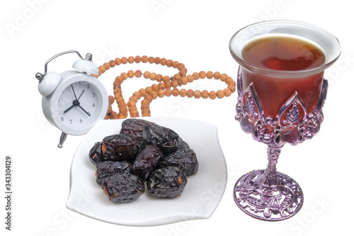 Dried dates fruits on a plate,  honeyc , ALARM CLOCK and prayer beads or tasbih isolated on white background. Fasting month Ramadhan concept. photo