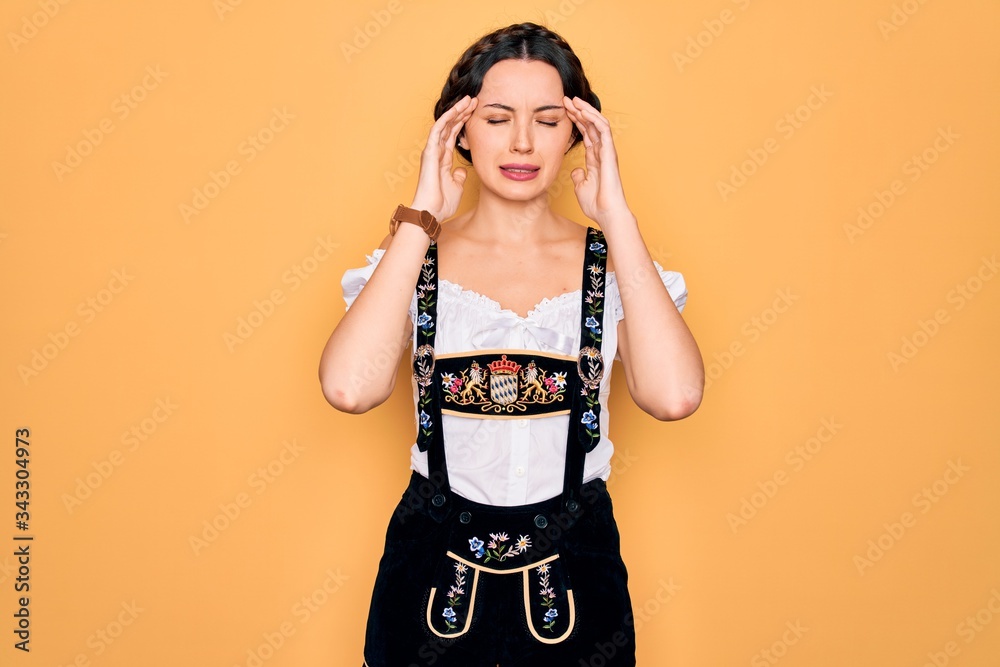 Young beautiful german woman with blue eyes wearing traditional octoberfest dress with hand on head for pain in head because stress. Suffering migraine. Young beautiful german woman with blue eyes wearing traditional octoberfest dress with hand on head for pain in head because stress. Suffering migraine.