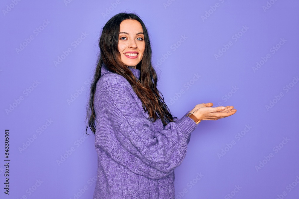 Young beautiful woman wearing casual turtleneck sweater standing over purple background pointing aside with hands open palms showing copy space, presenting advertisement smiling excited happy Young beautiful woman wearing casual turtleneck sweater standing over purple background pointing aside with hands open palms showing copy space, presenting advertisement smiling excited happy