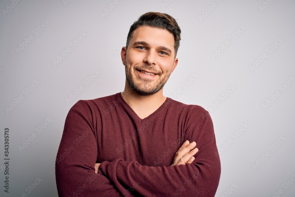 Young man with blue eyes wearing casual sweater standing over isolated background happy face smiling with crossed arms looking at the camera. Positive person. Young man with blue eyes wearing casual sweater standing over isolated background happy face smiling with crossed arms looking at the camera. Positive person.
