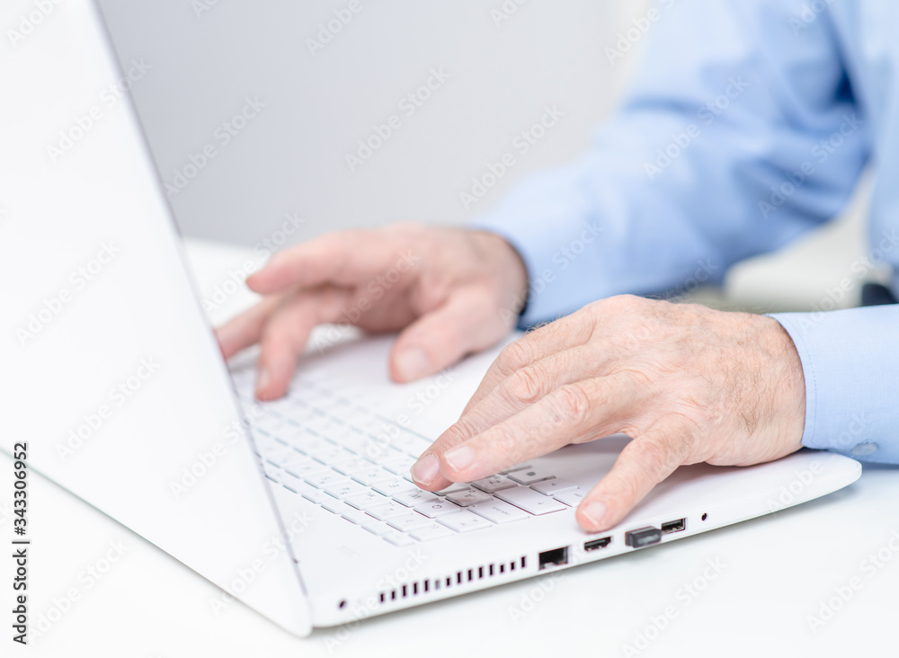 Elderly person works on laptop in a office Elderly person works on laptop in a office