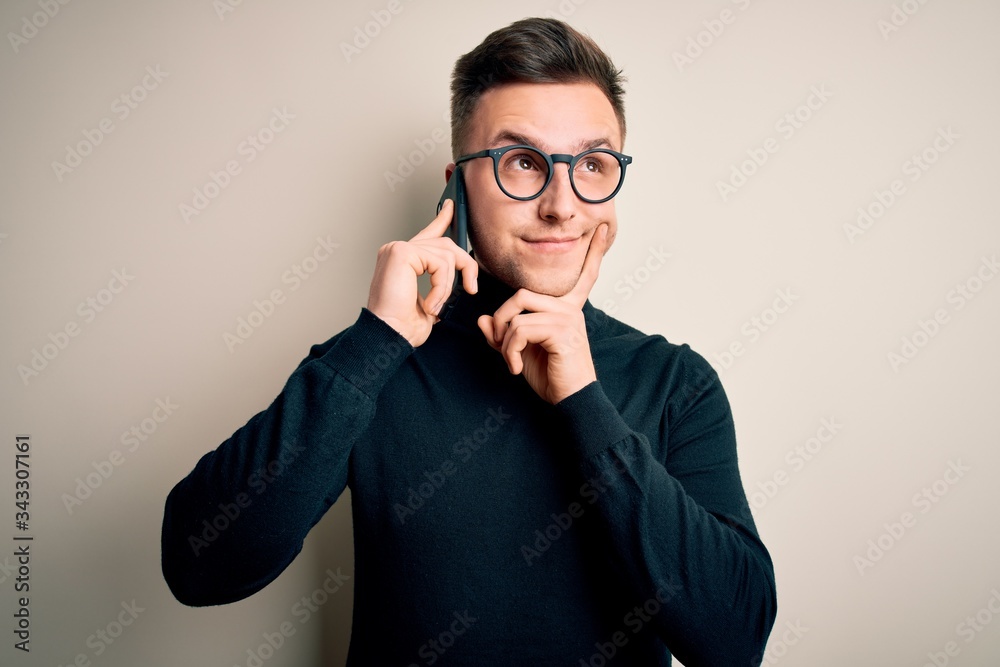 Young handsome caucasian man having a conversation talking on smartphone serious face thinking about question, very confused idea Young handsome caucasian man having a conversation talking on smartphone serious face thinking about question, very confused idea