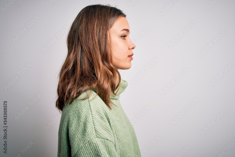 Young beautiful blonde girl wearing winter sweater standing over isolated background looking to side, relax profile pose with natural face with confident smile. Young beautiful blonde girl wearing winter sweater standing over isolated background looking to side, relax profile pose with natural face with confident smile.