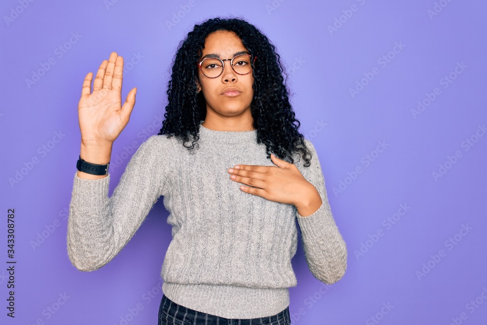 Young african american woman wearing casual sweater and glasses over purple background Swearing with hand on chest and open palm, making a loyalty promise oath Young african american woman wearing casual sweater and glasses over purple background Swearing with hand on chest and open palm, making a loyalty promise oath