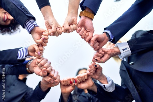 Group of business workers standing bumping fists at the office © Krakenimages.com