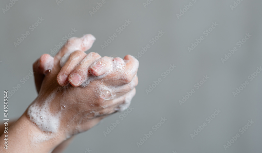 Closeup of person washing hands on gray background. Empty space for text Closeup of person washing hands on gray background. Empty space for text