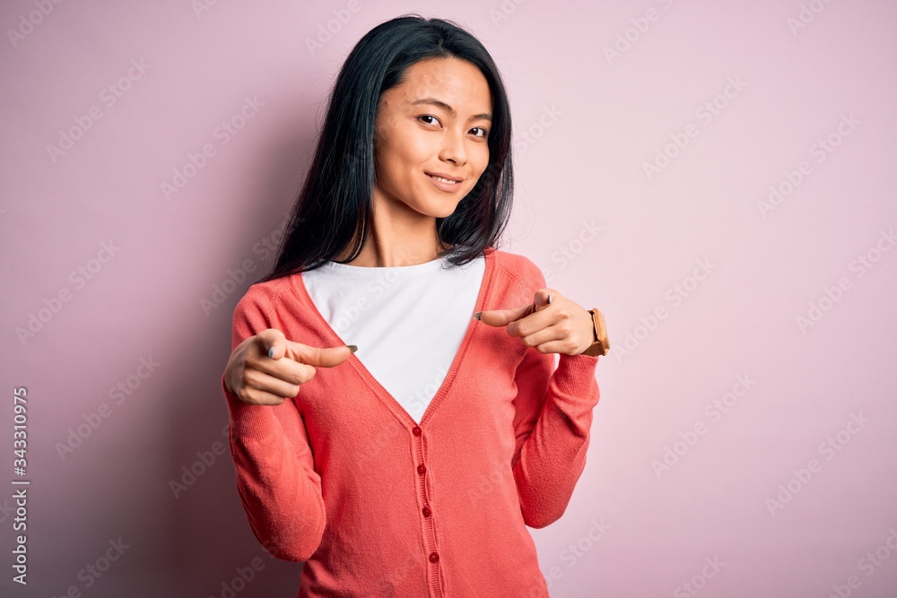 Young beautiful chinese woman wearing casual sweater over isolated pink background pointing fingers to camera with happy and funny face. Good energy and vibes. Young beautiful chinese woman wearing casual sweater over isolated pink background pointing fingers to camera with happy and funny face. Good energy and vibes.