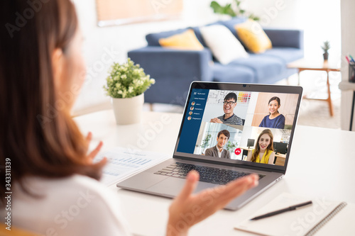 Young Asian businesswoman work at home and virtual video conference meeting with colleagues business people, online working, video call due to social distancing photo