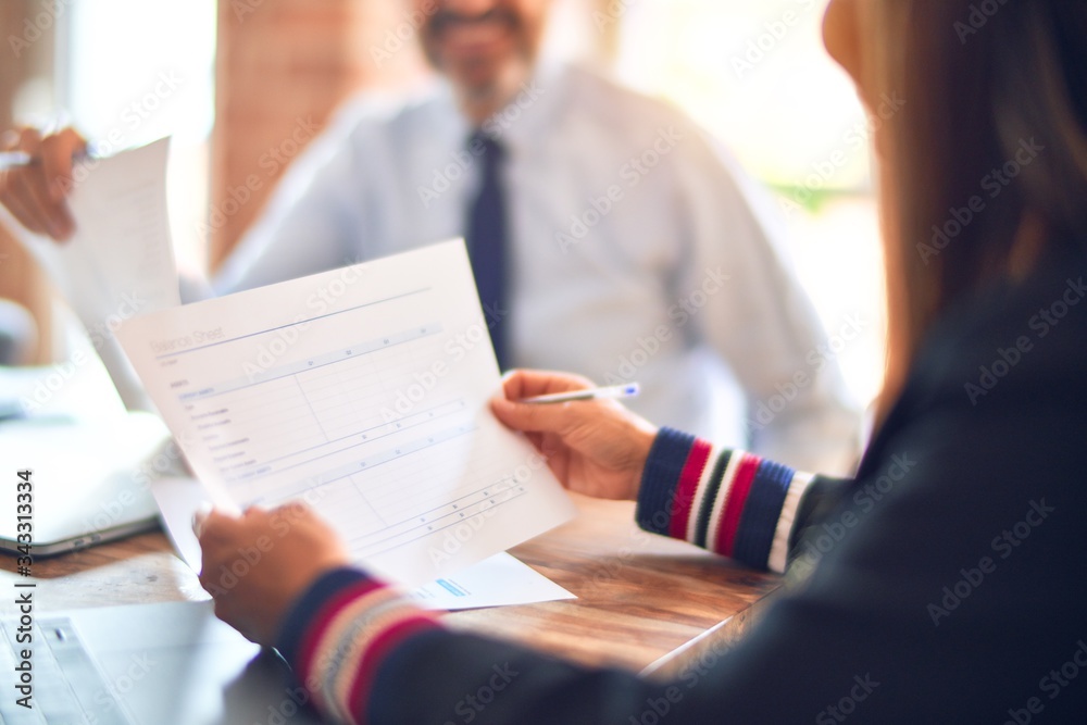 Two middle age business workers smiling happy and confident. Working together with smile on face using laptop at the office Two middle age business workers smiling happy and confident. Working together with smile on face using laptop at the office
