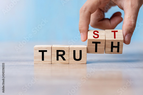 Businessman hand change wooden cube block with TRUST and TRUTH business word on table background. Trustworthy, Truth, beliefs and agreement concept photo