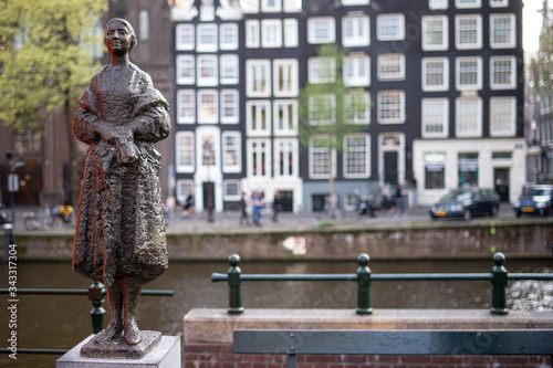 Piccola statua scultura in bronzo di donna in piedi vestita e avvolta nel suo scialle posta lungo un canale in città photo