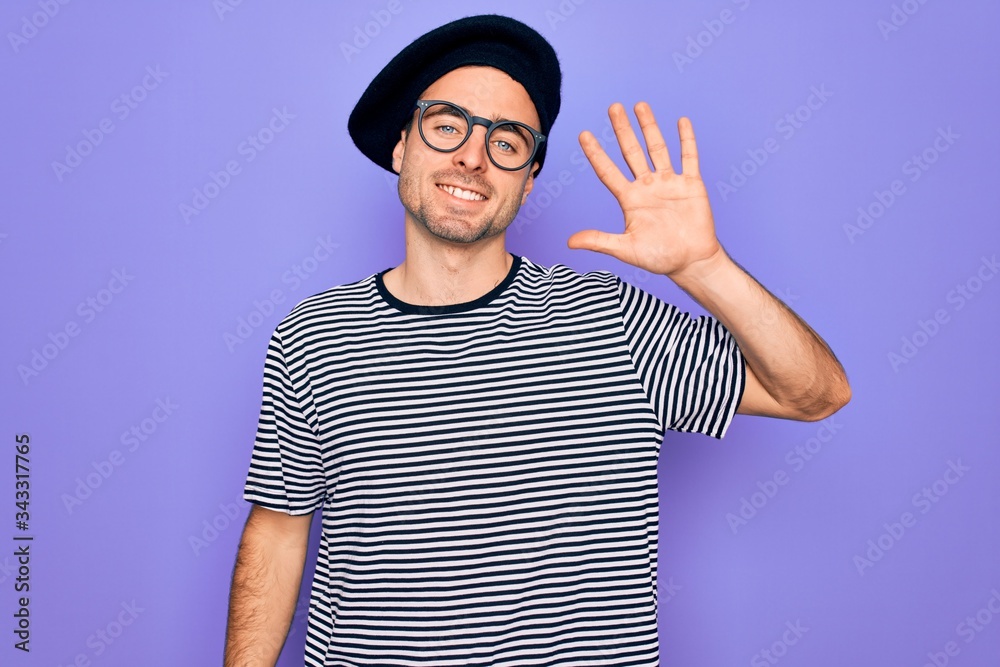 Handsome man with blue eyes wearing striped t-shirt and french beret over purple background showing and pointing up with fingers number five while smiling confident and happy. Handsome man with blue eyes wearing striped t-shirt and french beret over purple background showing and pointing up with fingers number five while smiling confident and happy.