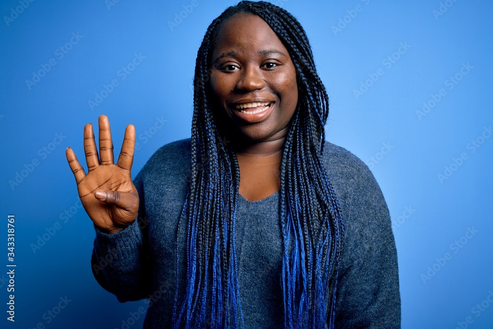 African american plus size woman with braids wearing casual sweater over blue background showing and pointing up with fingers number four while smiling confident and happy. African american plus size woman with braids wearing casual sweater over blue background showing and pointing up with fingers number four while smiling confident and happy.
