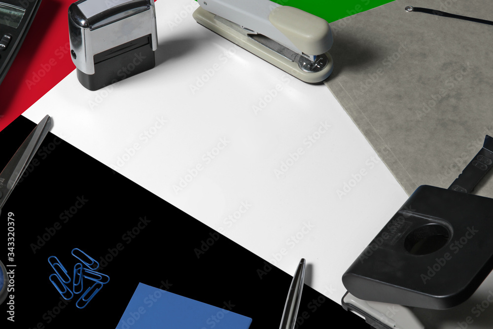 United Arab Emirates flag with office clerk workplace background. National stationary concept with office tools.