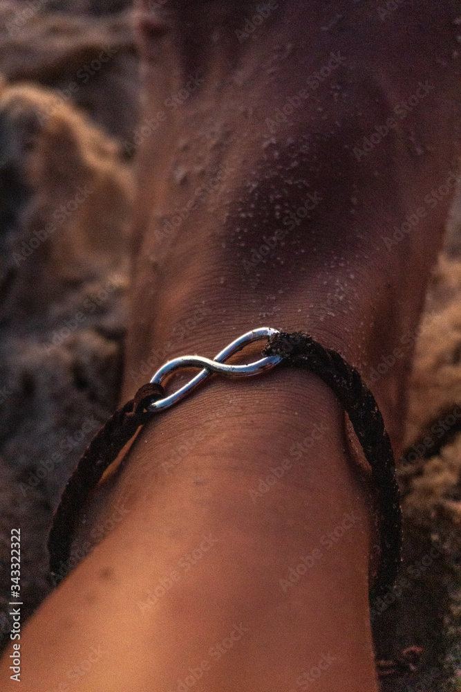 Female foot on the beach. Female anklet Female foot on the beach. Female anklet