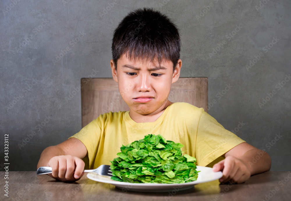 upset and disgusted hispanic kid sitting on table in front of spinach plate unhappy rejecting the fresh food finding it disgusting in child hate green vegetables concept upset and disgusted hispanic kid sitting on table in front of spinach plate unhappy rejecting the fresh food finding it disgusting in child hate green vegetables concept