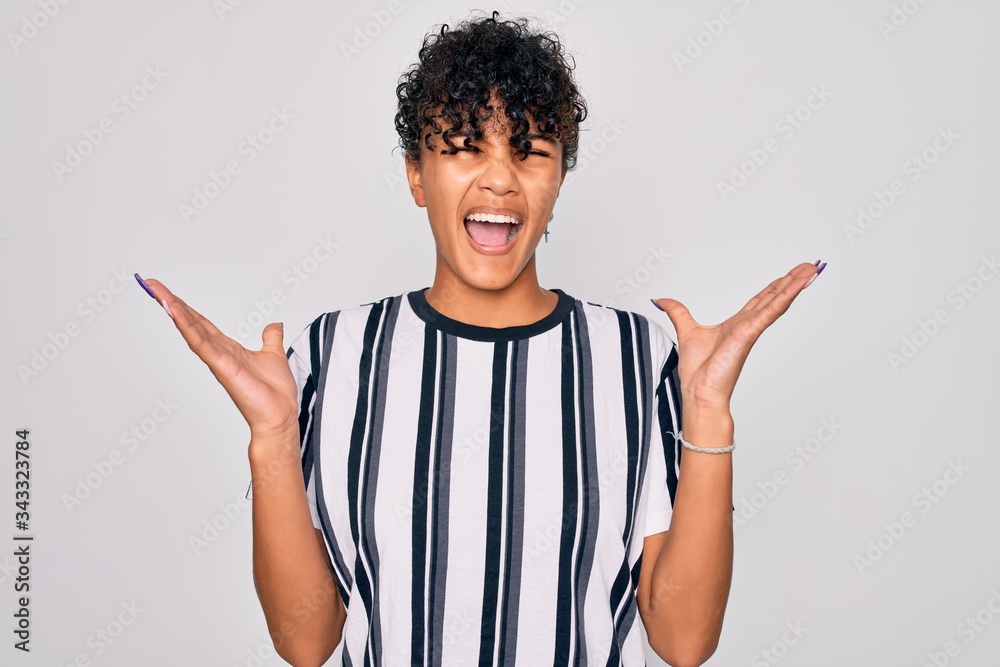 Beautiful african american afro woman wearing casual striped t-shirt over white background celebrating mad and crazy for success with arms raised and closed eyes screaming excited. Winner concept Beautiful african american afro woman wearing casual striped t-shirt over white background celebrating mad and crazy for success with arms raised and closed eyes screaming excited. Winner concept
