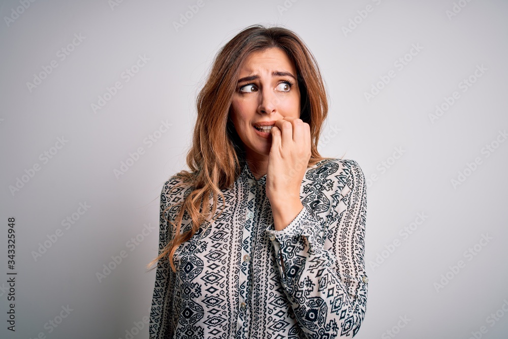 Young beautiful brunette woman wearing casual shirt standing over isolated white background looking stressed and nervous with hands on mouth biting nails. Anxiety problem.